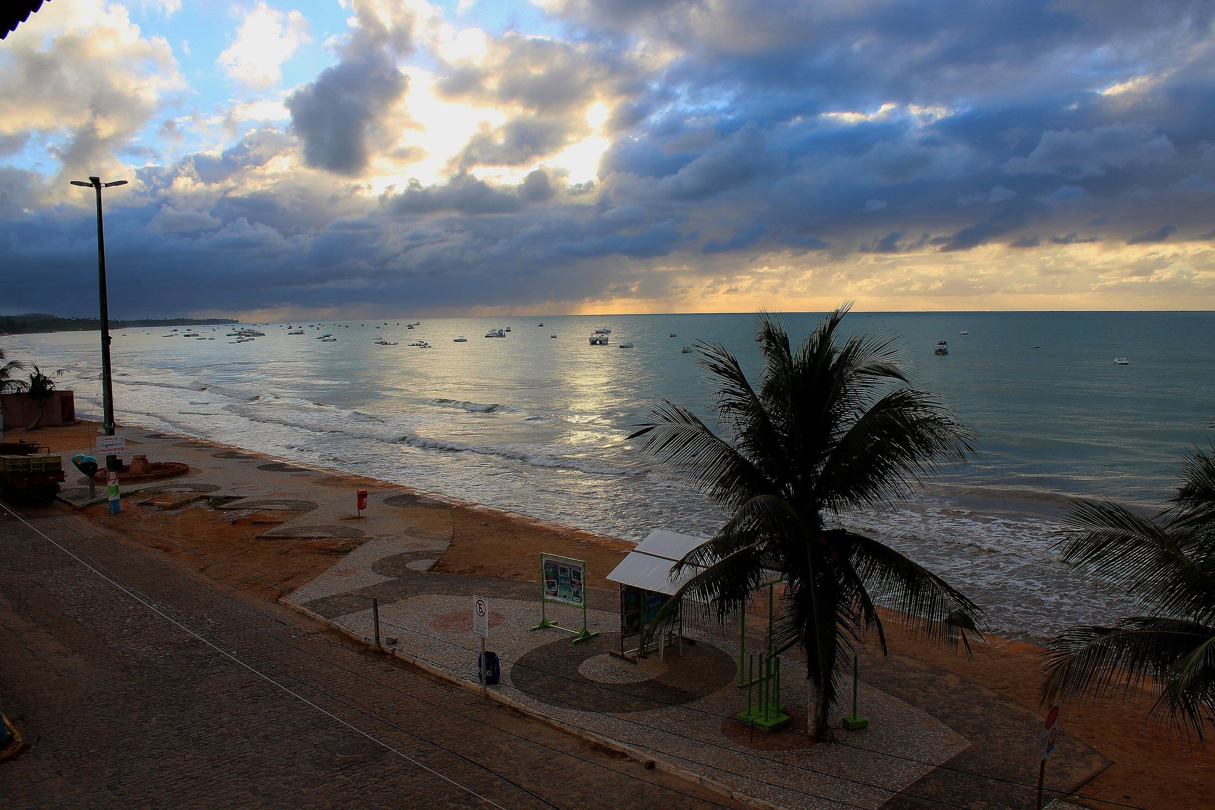 Amanhecer com nuvens de chuva sobre o mar e os barcos da orla de Maragogi