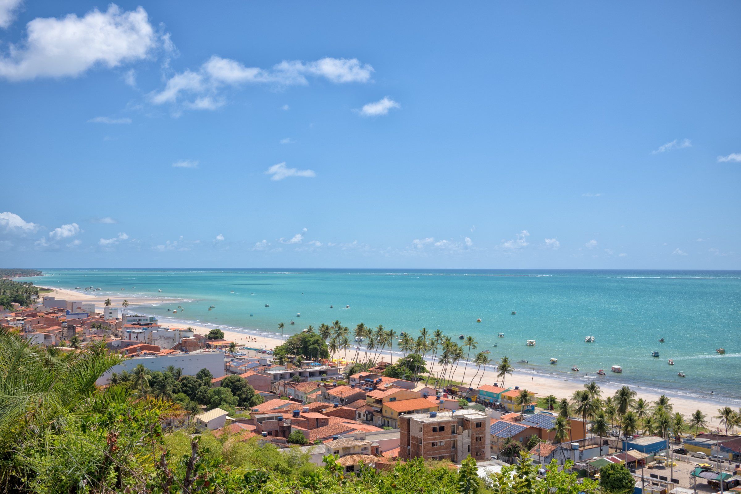 Vista do alto da Praia de Barra Grande, em Maragogi, com casas, coqueiros e o mar turquesa