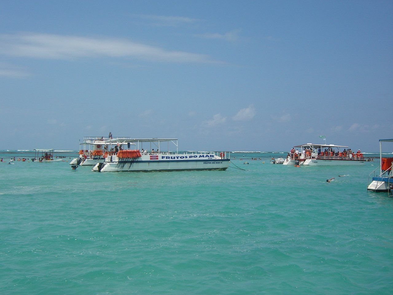 Catamarãs ancorados sobre a água turquesa das piscinas naturais de Maragogi