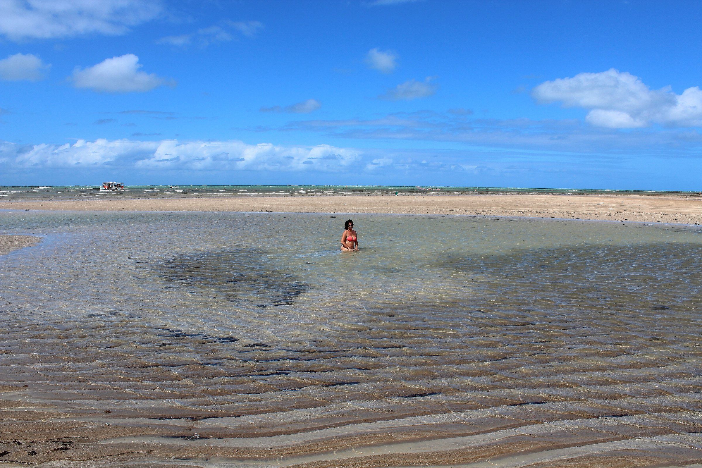 Banhista em piscina natural rasa formada na maré baixa no litoral de Maragogi