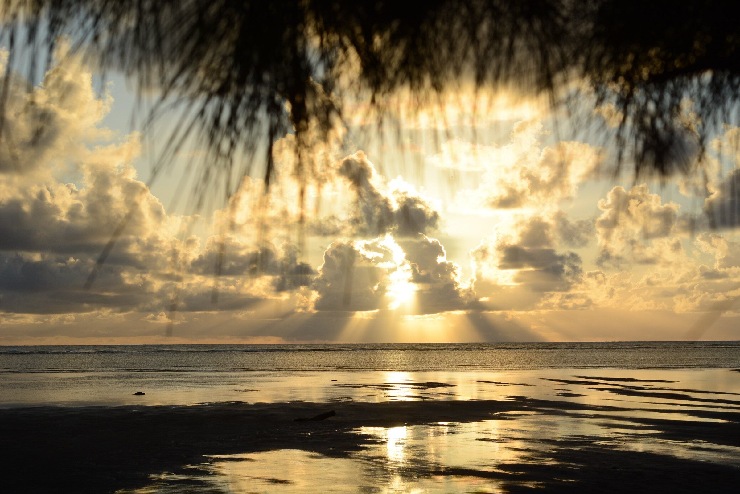 Sol entre nuvens refletido na água rasa da praia de Ponta de Mangue, em Maragogi